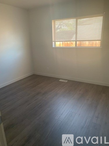A room with wooden flooring and a window with blinds.