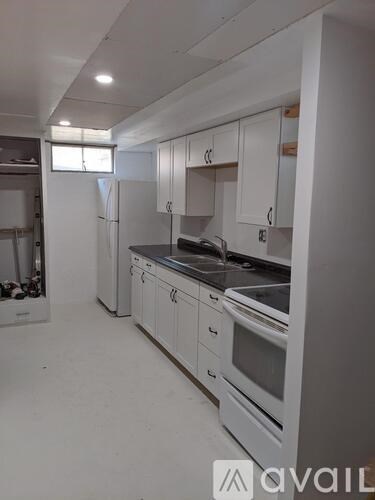A kitchen with white cabinets and appliances is available for rent.
