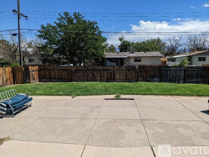 A backyard with a concrete patio and a blue bench.