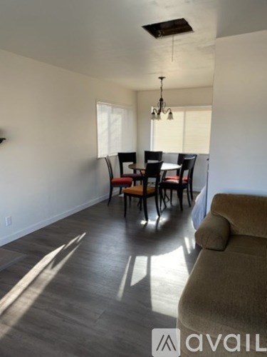 A living room with a brown couch and a dining table with chairs.