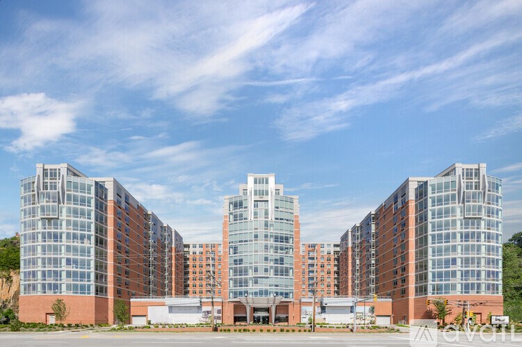 A large, modern building with a glass facade is surrounded by a parking lot.