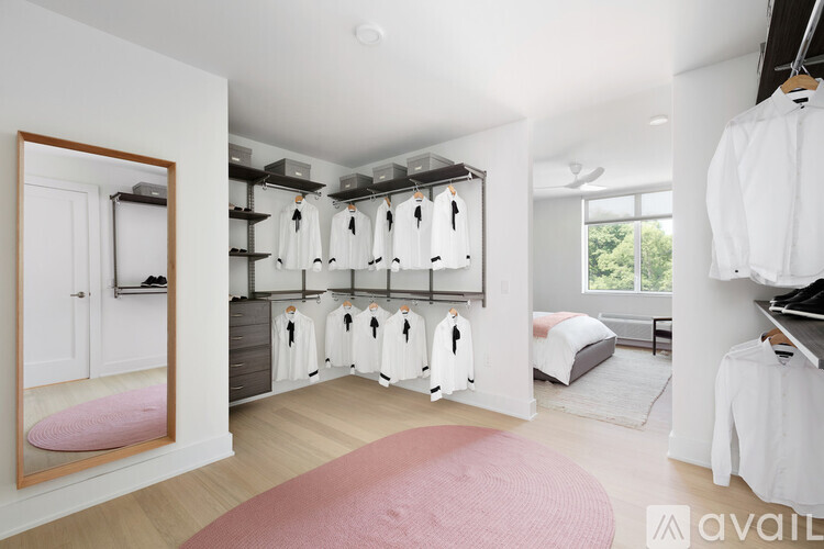 A bedroom with a pink rug and a bed with white sheets.