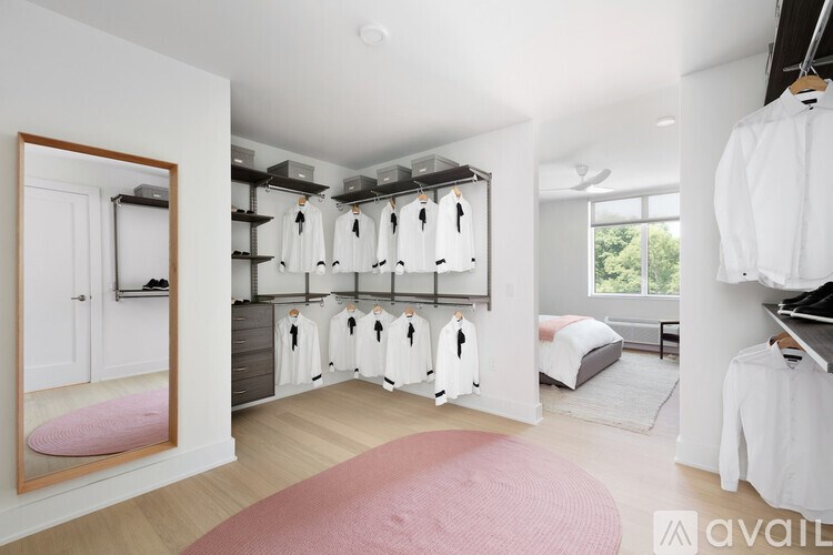 A bedroom with a pink rug and a bed with white sheets.