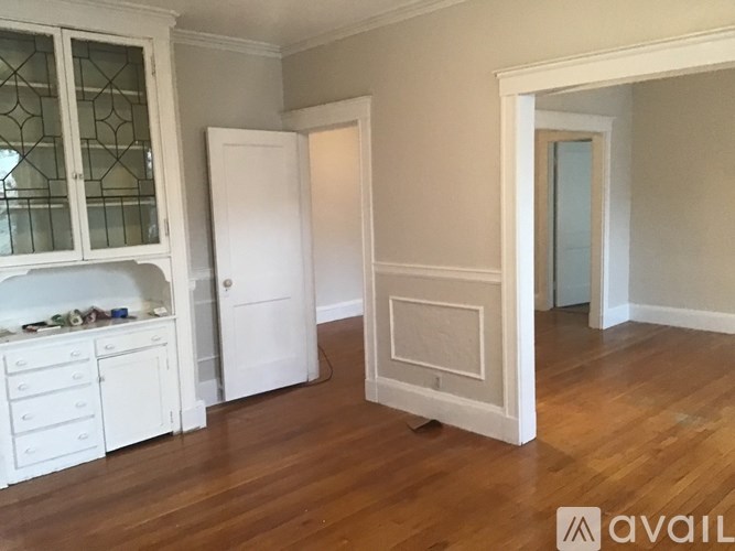 A room with a white door and a white cabinet with glass doors.