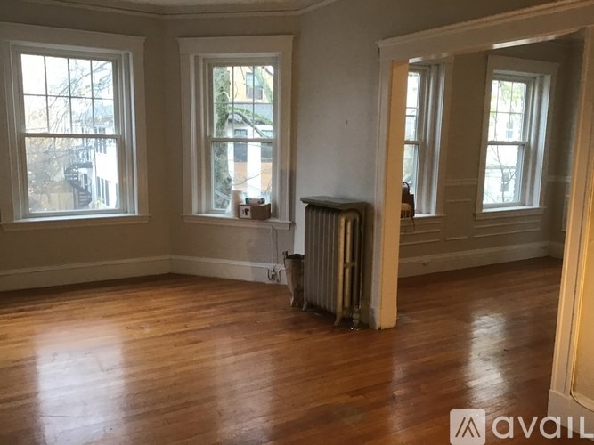 A room with wood floors and three windows.
