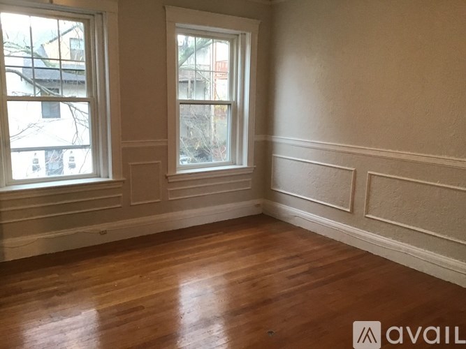 A room with wooden floors and two windows.