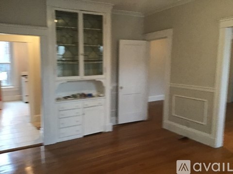 A kitchen with white cabinets and a wooden floor.