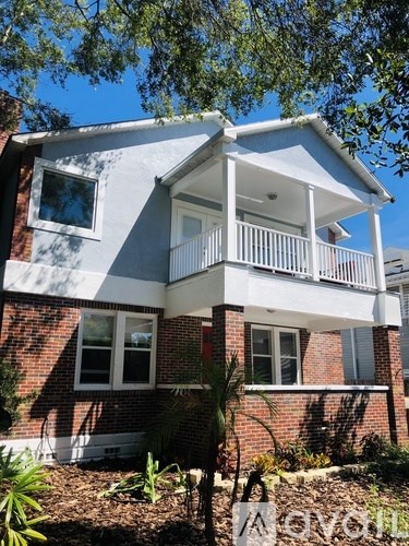 A house with a white balcony and a red brick exterior.
