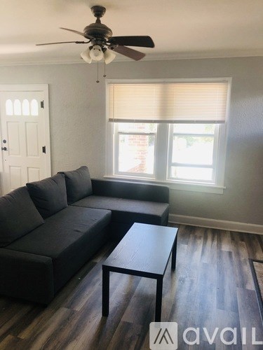 A living room with a black couch and a wooden coffee table.