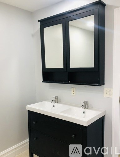 A white sink with a black cabinet and mirror above it.