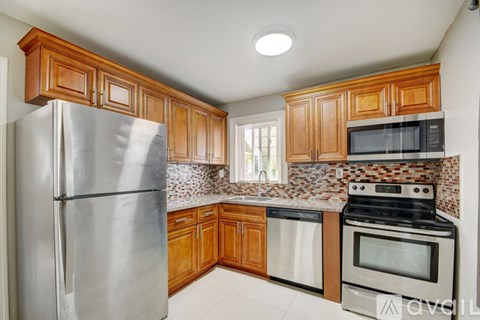 A kitchen with wooden cabinets and a stainless steel refrigerator.