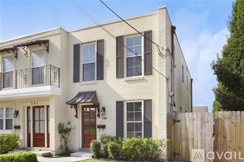 A two-story house with a balcony on the first floor and a small front porch.