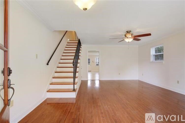 A room with wooden floors and a staircase leading to another room.