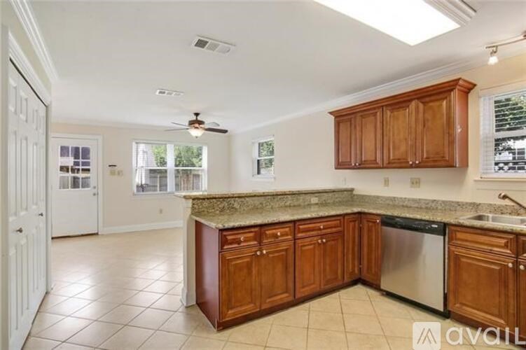 A kitchen with brown cabinets and a marble countertop.