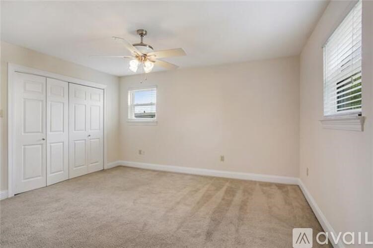 A room with a ceiling fan and carpeted floor.
