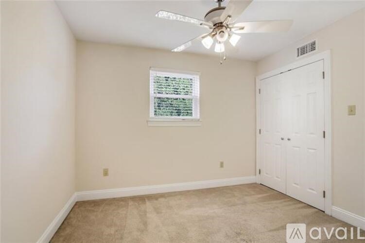 A room with a ceiling fan and a window with blinds.