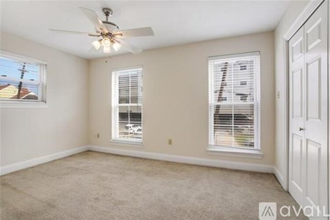 A room with a ceiling fan and two windows.