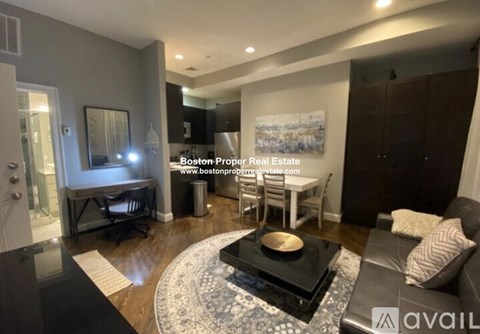 A modern living room with a black and white rug, a coffee table, and a painting on the wall.