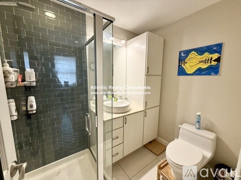 A bathroom with a toilet, sink, and shower.