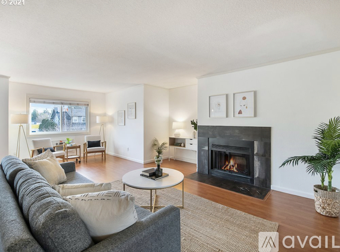 A living room with a grey couch, a fireplace, and a large window.