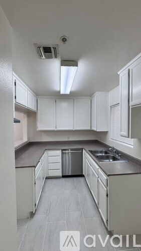 A kitchen with white cabinets and a grey floor.