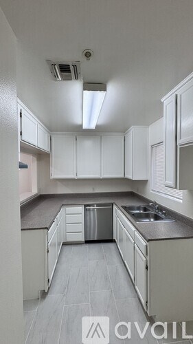 A kitchen with white cabinets and a grey floor.