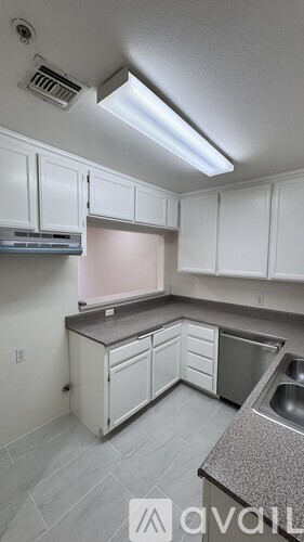 A kitchen with white cabinets and a stainless steel dishwasher.