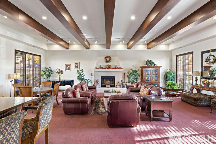 A large, well-lit living room with a fireplace and various seating arrangements.