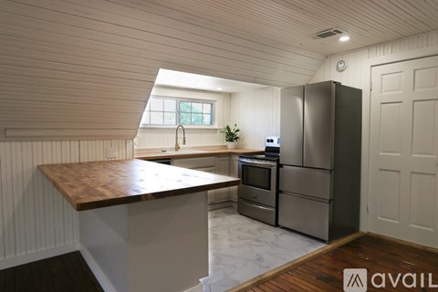 A kitchen with a wooden counter top and stainless steel appliances.