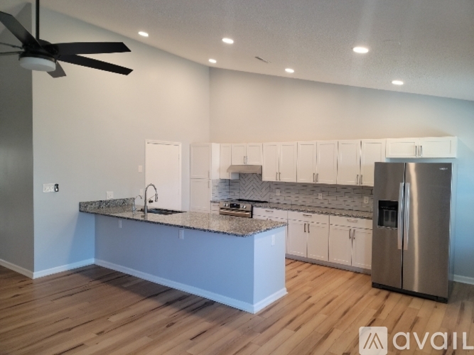 A kitchen with a refrigerator, sink, and cabinets.