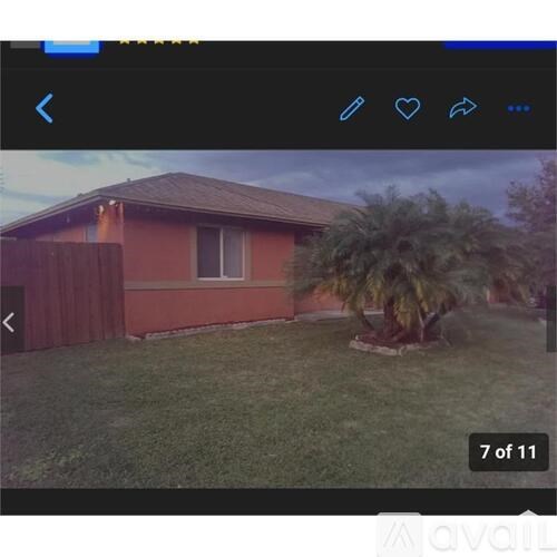 A house with a brown roof and a red wall with a tree in front.