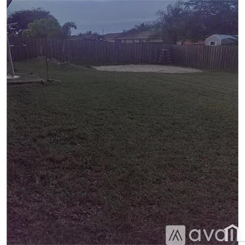 A backyard with a wooden fence and a green lawn.