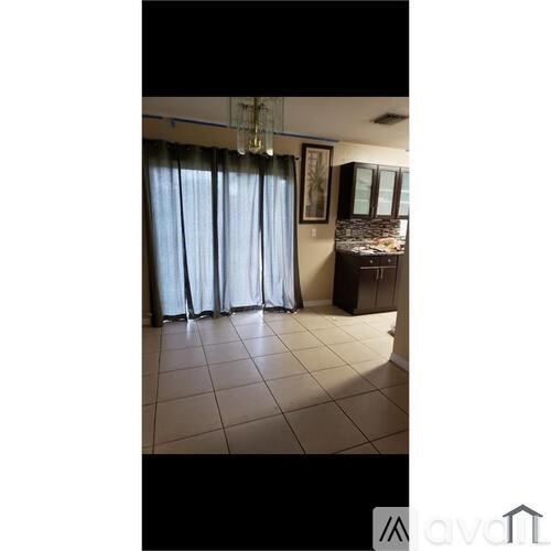 A room with a chandelier, a window with curtains, and a cabinet with a mirror.