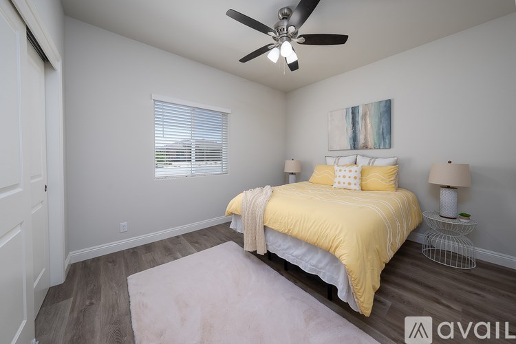 A bedroom with a yellow bedspread and a ceiling fan.