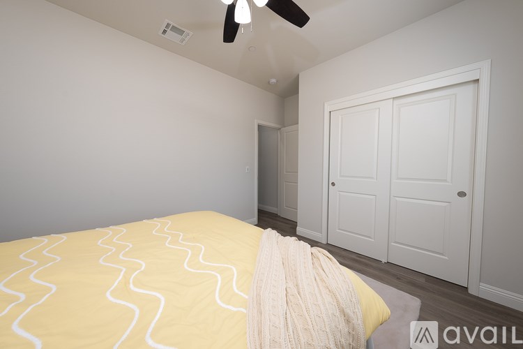 A bedroom with a bed covered in a yellow and white patterned comforter.