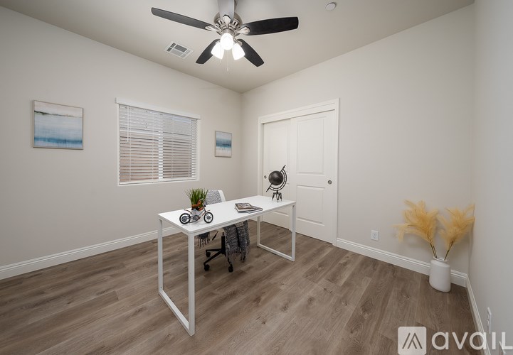 A room with a white desk and a ceiling fan.