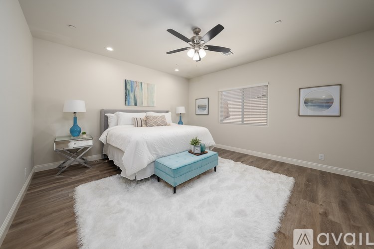A bedroom with a white bed, a ceiling fan, and a white rug.
