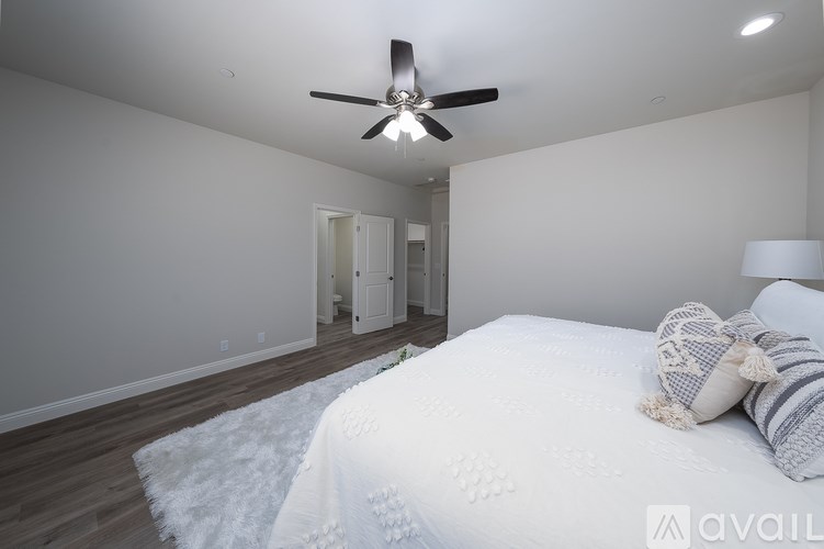 A bedroom with a bed, a ceiling fan, and a white rug.
