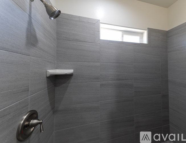 A shower area with a wall-mounted shower head and a handheld shower head.