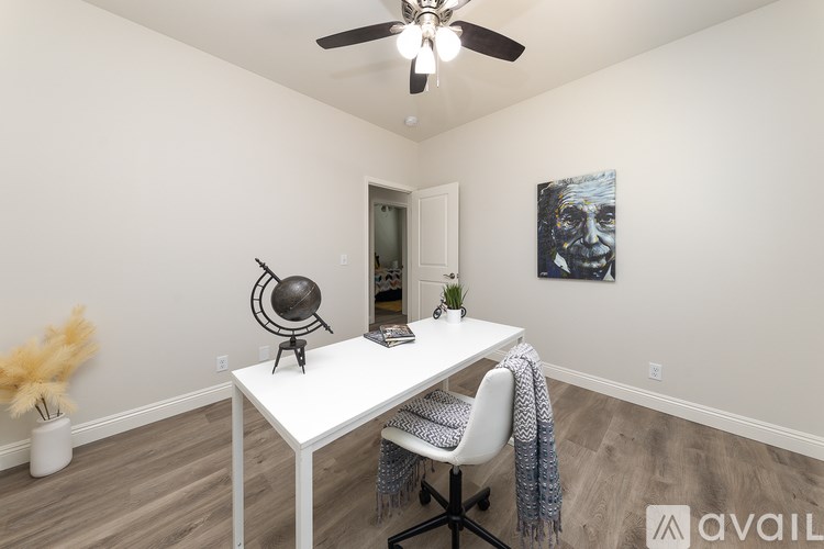 A room with a white desk and a ceiling fan.