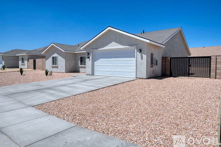 A house with a white garage door is surrounded by a gravel driveway.