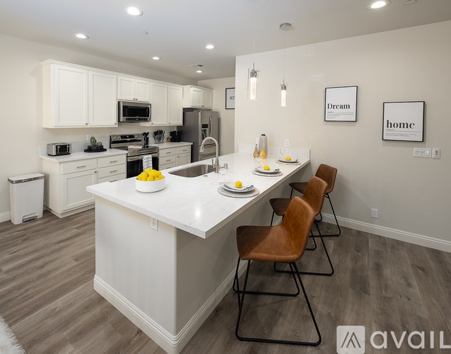 A modern kitchen with a white island and brown chairs.