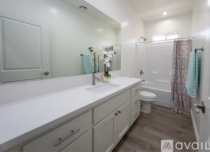 A bathroom with a sink, mirror, toilet, and shower.