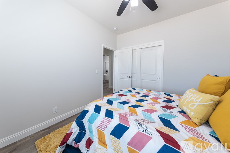 A bedroom with a bed covered in a quilt and two yellow pillows.