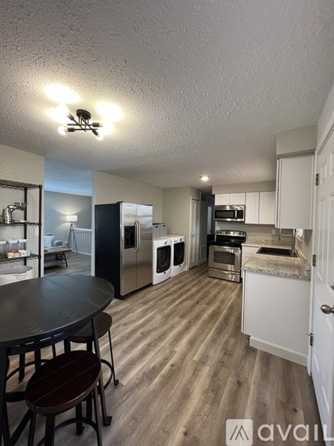 A kitchen with a table and chairs in the foreground and a microwave, oven, and sink in the background.