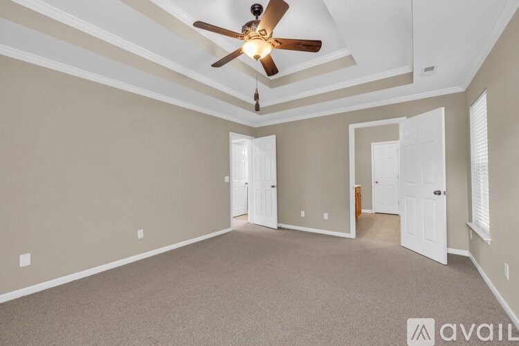 A spacious room with a ceiling fan and three doors.