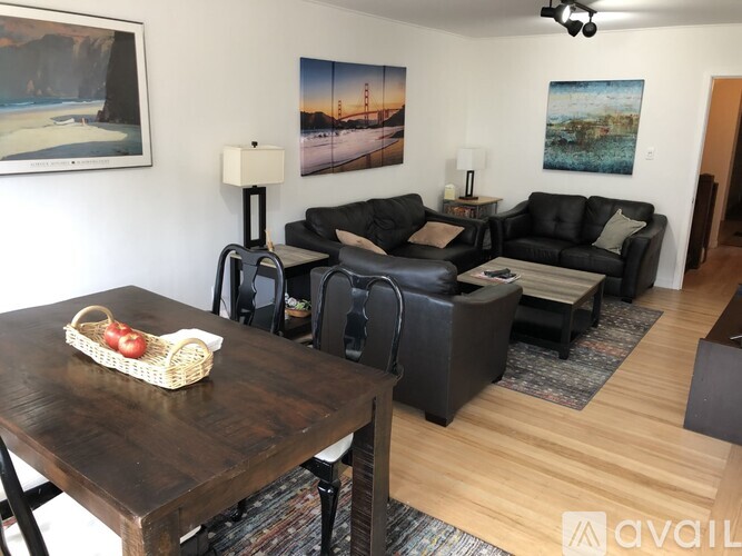 A living room with a wooden table and black leather couches.