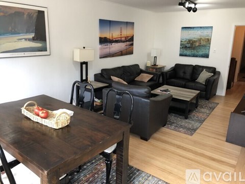 A living room with a wooden table and black leather couches.