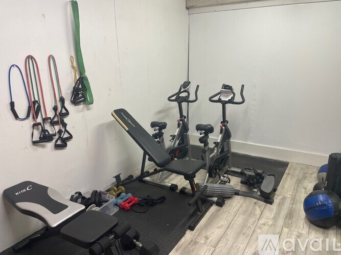 A gym room with exercise equipment and a wall-mounted rack of resistance bands.