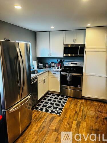 A kitchen with a stainless steel refrigerator and wooden floors.